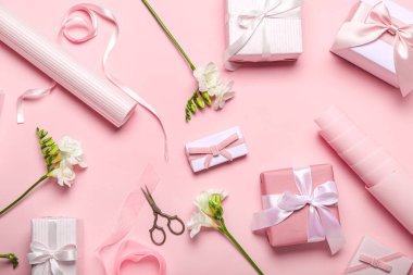 Composition with gift boxes, wrapping paper and freesia flowers on pink background. Women's Day celebration