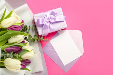 Envelope with blank card, gift and bouquet of beautiful tulip flowers on pink background. Hello spring