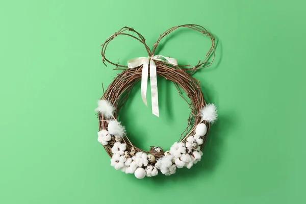 Easter wreath with cotton flowers and quail eggs on green wall