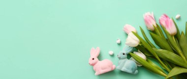 Bouquet of beautiful flowers, eggs and Easter toy bunnies on turquoise background with space for text
