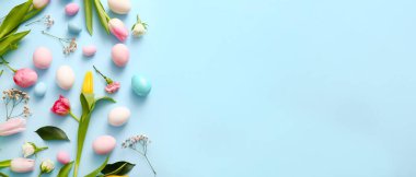 Many beautiful flowers and Easter eggs on light blue background with space for text