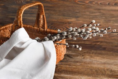 Pussy willow branches in wicker basket on wooden background