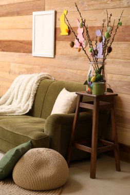 Interior of living room decorated for Easter celebration with sofa and willow branches in vase