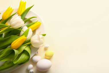 Plate with beautiful tulip flowers and Easter eggs on color background