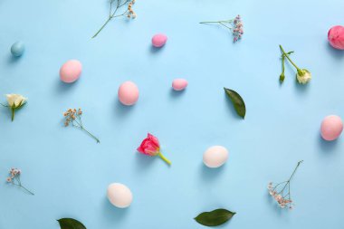 Composition with painted Easter eggs and flowers on color background