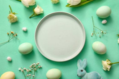 Composition with empty plate Easter eggs and flowers on color background
