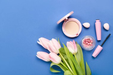 Composition with tulip flowers, cosmetics and makeup sponges on blue background