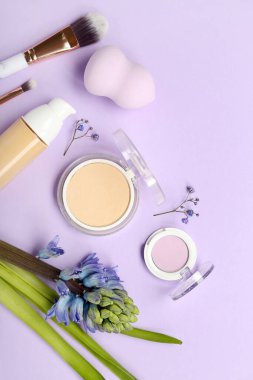 Composition with cosmetics, makeup accessories and hyacinth flower on lilac background