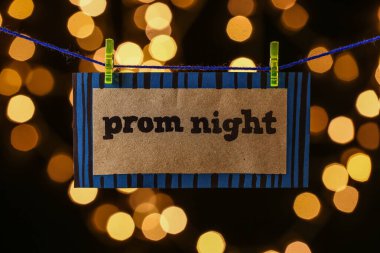 Rope with clothespins and text PROM NIGHT against blurred lights