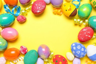 Frame made of painted Easter eggs and serpentine on yellow background