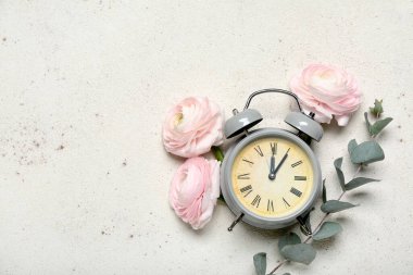 Composition with alarm clock, beautiful ranunculus flowers and eucalyptus branch on light background