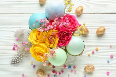 Beautiful composition with Easter eggs and flowers on light wooden background