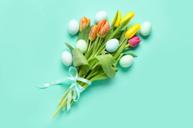 Bouquet of beautiful tulip flowers and Easter eggs on color background