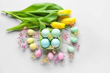 Composition with painted Easter eggs and flowers on white background