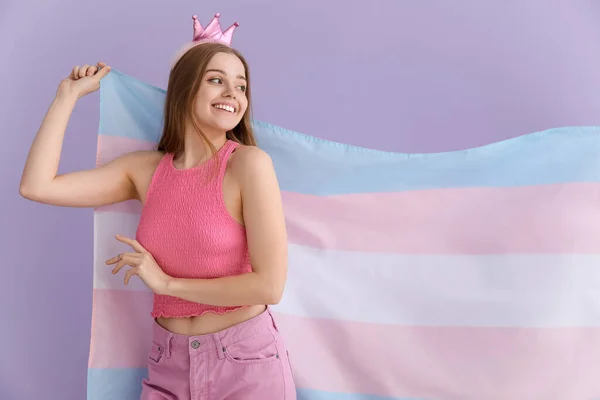 Young woman in crown with transgender flag on lilac background