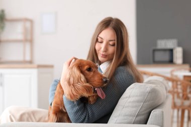 Young woman with red cocker spaniel sitting on sofa in kitchen