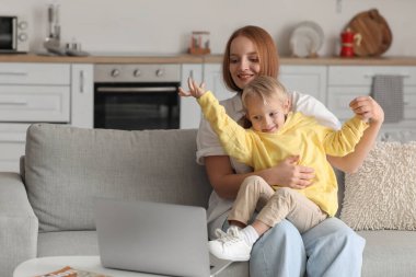 Mother with her little son watching cartoons at home