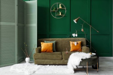 Vase with branches and painted Easter eggs on table in living room