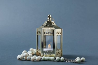 Muslim lantern with candle and prayer beads for Ramadan on dark background