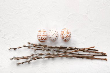 Beautiful Easter eggs with willow branches on light background