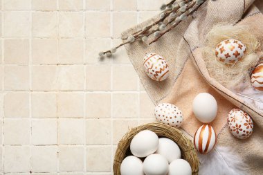 Composition with beautiful Easter eggs and willow branches on light tile