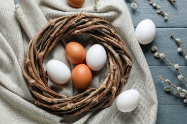 Composition with Easter eggs, wreath and willow branches on color wooden background