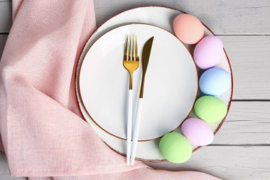 Table serving with Easter eggs on white wooden background