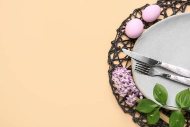 Table setting with Easter eggs, cutlery and hyacinth flowers on beige background