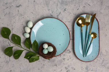 Table serving with Easter eggs and green plant branch on grey grunge background