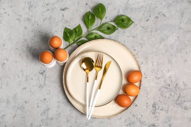 Table serving with Easter eggs and green plant branch on grey grunge background