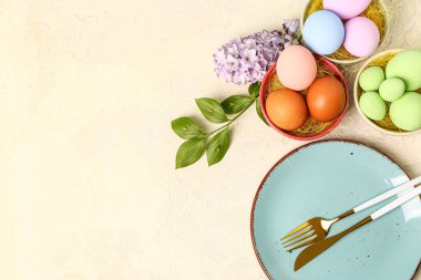Table serving with Easter eggs, hyacinth flowers and plant branch on beige background
