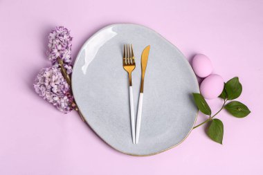 Table serving with Easter eggs, hyacinth flowers and green plant branch on lilac background