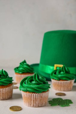 Tasty cupcakes for St. Patrick's Day, leprechaun hat and coins on white background