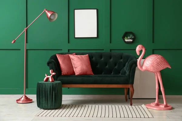 Interior of living room with pink flamingo, stylish sofa and standard lamp near green wall