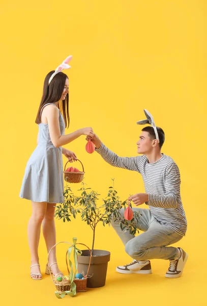 Šťastný Mladý Pár Zajíček Uši Velikonočními Vejci Žlutém Pozadí — Stock fotografie