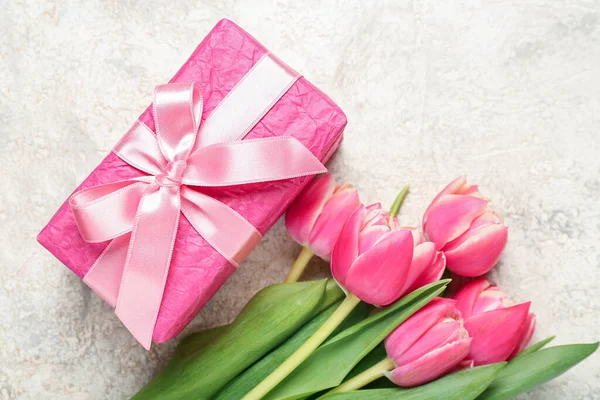 Gift box and beautiful tulip flowers on grunge background. Hello spring