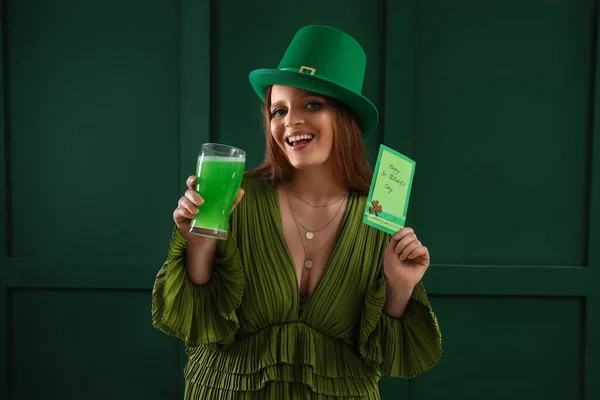 Beautiful woman holding card with text HAPPY ST. PATRICK\'S DAY and beer on green background