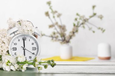 Çalar saat ve çiçekler masada. Bahar geldi.