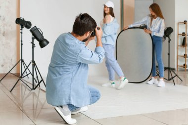 Male photographer and his assistant working with beautiful model in studio