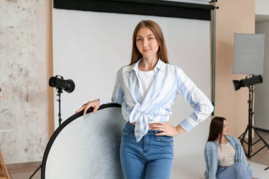Female assistant with equipment in photo studio
