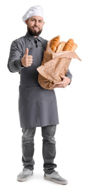 Male baker with fresh baguettes showing thumb-up on white background