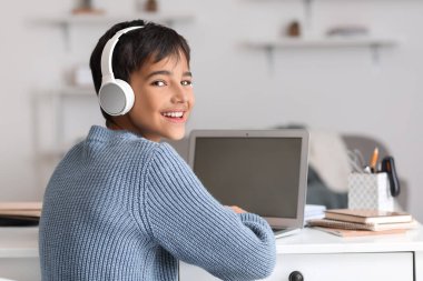 Little boy in headphones using laptop at home