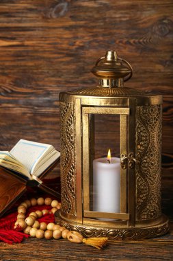 Muslim lantern with Koran and prayer beads for Ramadan on wooden table