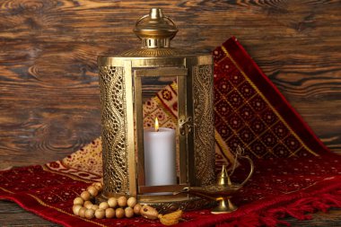 Mat with Muslim lantern, lamp and prayer beads for Ramadan on dark wooden background