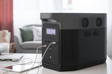 Portable power station charging gadgets on table in living room