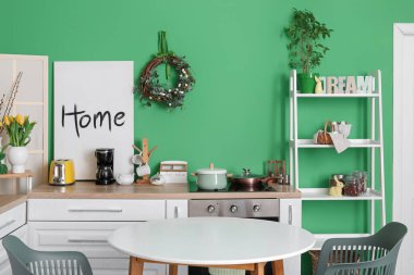 Interior of stylish kitchen with Easter wreath and dining table