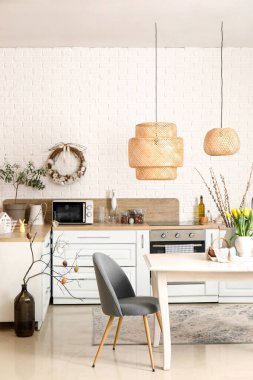 Interior of light kitchen with Easter decor, dining table and white counters