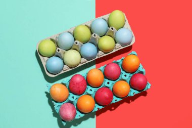 Cardboard holders with painted Easter eggs on color background