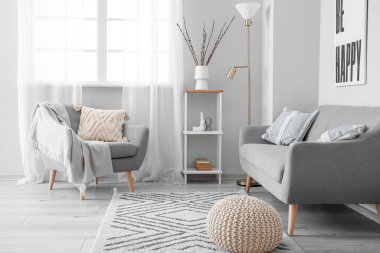 Interior of light living room with willow branches in vase and sofa