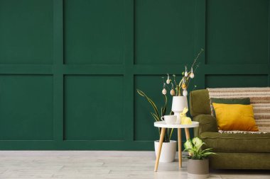 Vase with tree branches, Easter eggs, rabbit and cup on table in living room